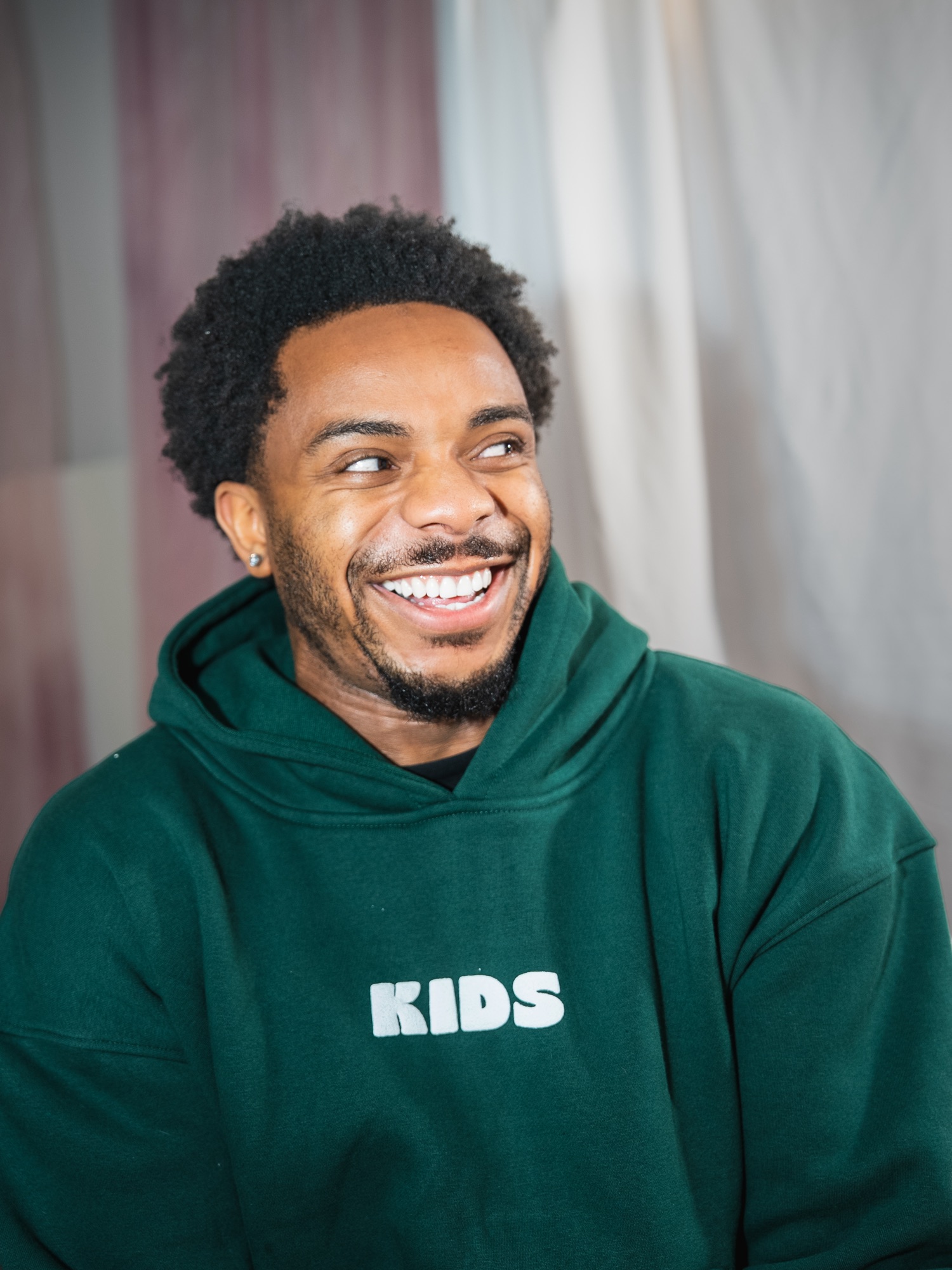 Killian laughing in the dark green KIDS hoodie
