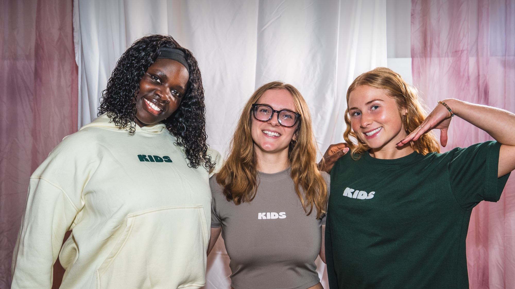 Three friends in the cream, stone and green Kids Like Us pieces at the Minneapolis pop-up