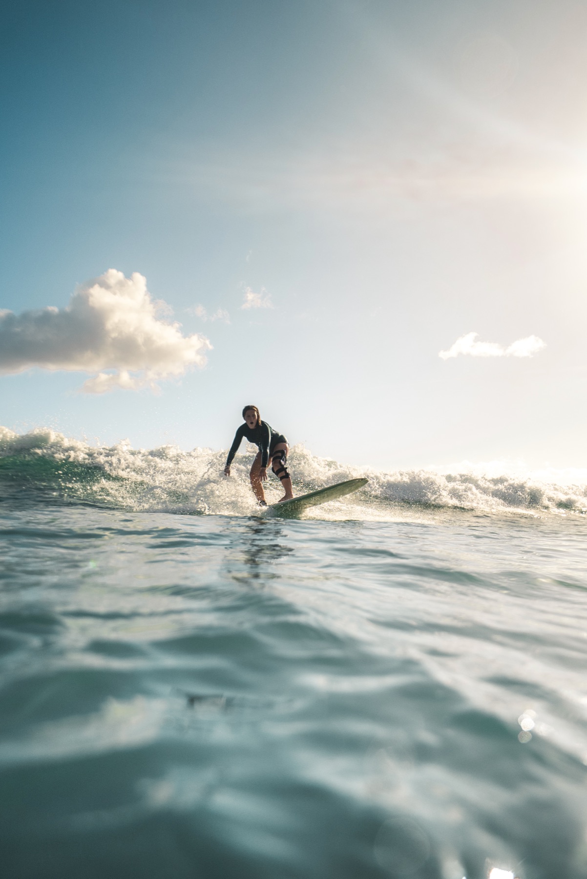 Syd Meyer surfing a wave at Waikiki in her knee brace
